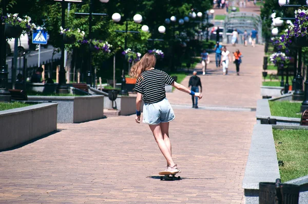 スレンダーティーン女の子乗りますAスケートボードダウンヨーロッパの街の中心部にある公園の路地に晴れた夏の日 — ストック写真