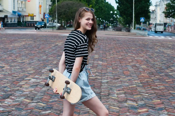 ヨーロッパの街の中心部にスケートボードを持つかなりティーンの女の子 — ストック写真