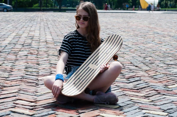 스케이트보드를 귀여운 소녀가 여름날 광장의 중앙에 — 스톡 사진