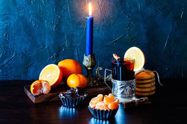 Noel zamanı, kış, cam ve bardak tutacağında şarap, tarçın, portakal ve mandalina, kurabiye ve çikolata. Mumlarla dolu bir hayat