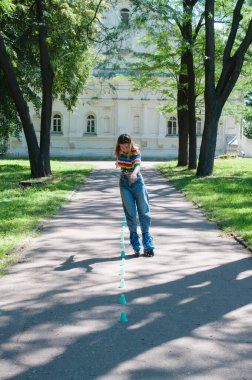 Güzel kız yazın parkta paten kayarken, vyponyaet numaraları yaparken ve çipleri gezerken eğleniyor..