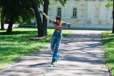 Güzel kız yazın parkta paten kayarken, vyponyaet numaraları yaparken ve çipleri gezerken eğleniyor..