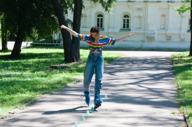 Güzel kız yazın parkta paten kayarken, vyponyaet numaraları yaparken ve çipleri gezerken eğleniyor..