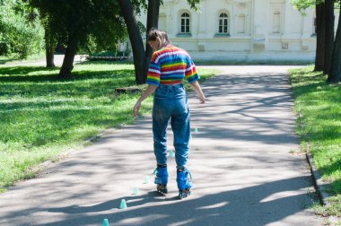 Güzel kız yazın parkta paten kayarken, vyponyaet numaraları yaparken ve çipleri gezerken eğleniyor..