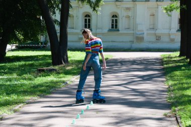 Güzel kız yazın parkta paten kayarken, vyponyaet numaraları yaparken ve çipleri gezerken eğleniyor..
