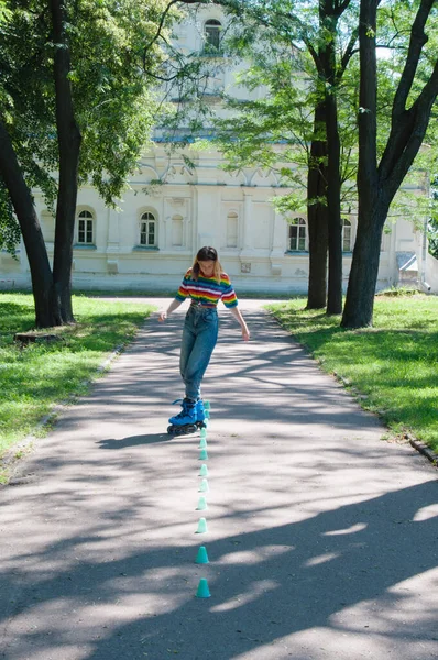Güzel kız yazın parkta paten kayarken, vyponyaet numaraları yaparken ve çipleri gezerken eğleniyor..