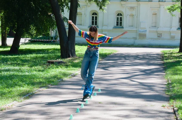 Güzel kız yazın parkta paten kayarken, vyponyaet numaraları yaparken ve çipleri gezerken eğleniyor..