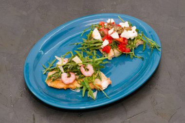 Gri arka planda karides, roka, domates, peynir ve sos, üst manzara. Yüksek İtalyan mutfağı