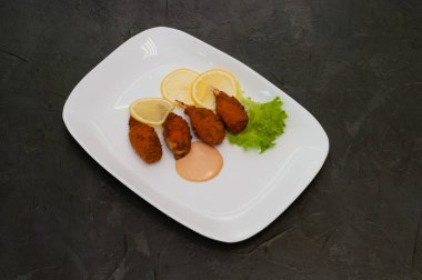 Limon, marul ve lezzetli tatlı ve ekşi sosla kızartılmış yengeç pençeleri. İtalyan mutfağının şenlikli yemekleri.