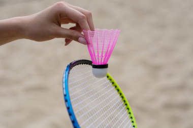 Badminton raketi ve kadın el çekimleri. Yaz etkinliği ve plaj eğlencesi konsepti.