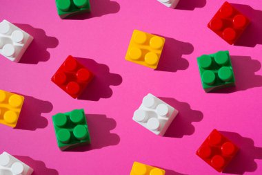 Pembe arka planda bir çocuk inşaatçısının çok renkli plastik blokları..