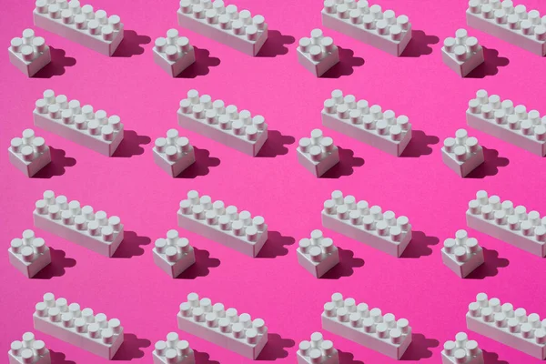 Modello di blocchi di plastica bianchi di costruttori per bambini su uno sfondo rosa — Foto Stock