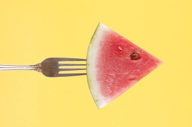 Bir dilim karpuz bir çatal sarı bir arka plan üzerinde bir kavram görüntüsünü.