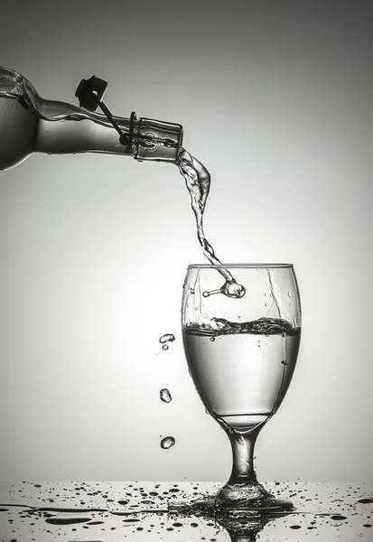 Studio concept image of pouring water from an old glass bottle into a glass.