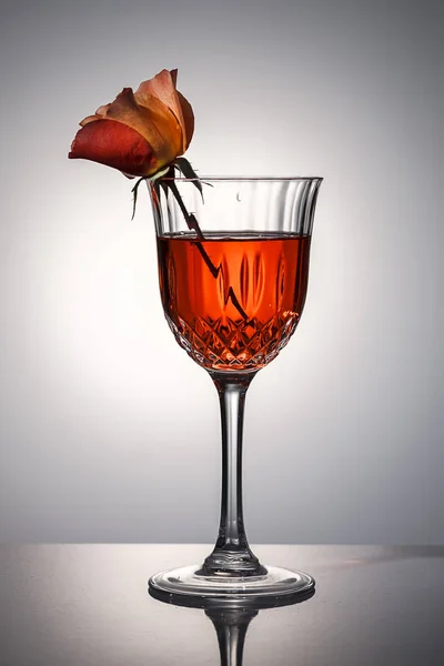 Eine Orangefarbene Rose Sitzt Einem Kristallweinglas Mit Rotem Wasser — Stockfoto