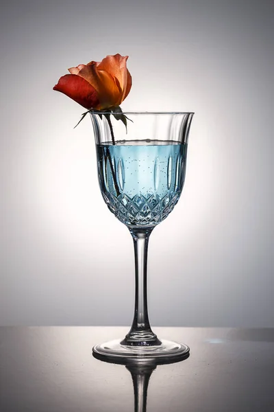 Une Rose Est Dans Verre Cristal Avec Eau Teintée Bleu — Photo