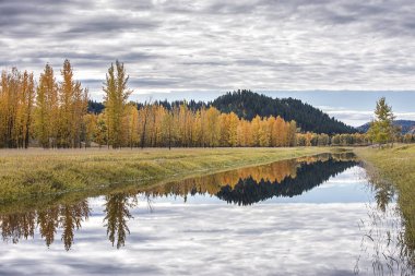 Bonners Ferry, Idaho yakınındaki bir sonbahar gününde gökyüzünde bulutlar sakin su kanalı'nın yansıtır.