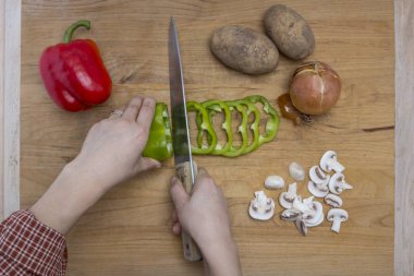 Bir kesme tahtası üzerinde çeşitli sebze kesme işlemi.
