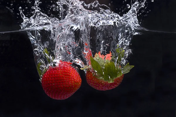 Dos fresas arrojadas al agua . —  Fotos de Stock