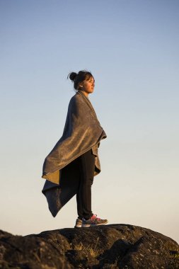 Altın ışıkta battaniyeye sarılmış genç.