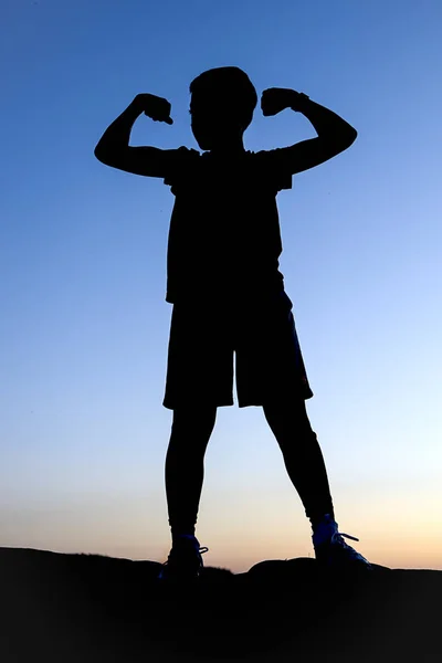 Silhouette of boy making a muscle pose. — Stock Photo, Image