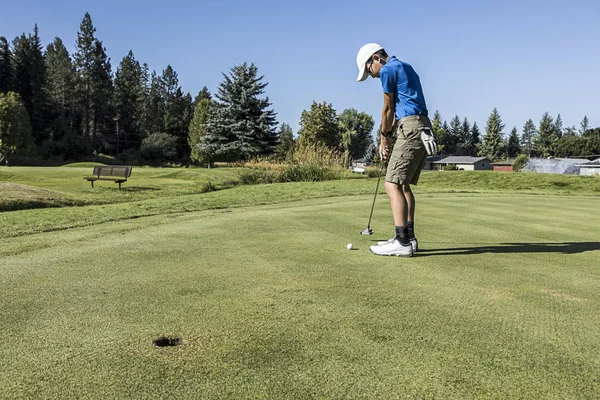Boy swings back for a putt. — Stock Photo, Image