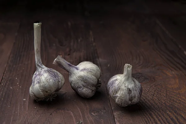 Три луковицы чеснока на деревянном столе . — стоковое фото