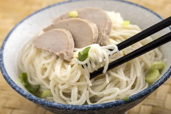 Using chopsticks to eat noodles and pork. — Stock Photo, Image