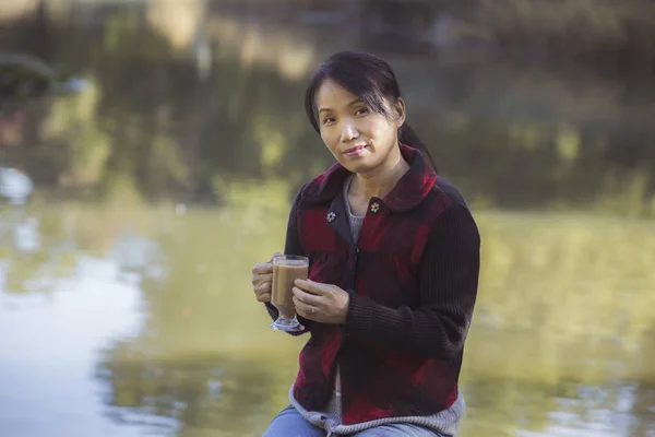 Kvinna med kaffe av dammen. — Stockfoto