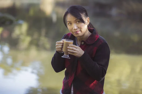 Mulher desfrutando de sua xícara de café junto à água . — Fotografia de Stock