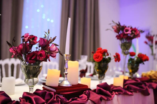 Restoran düğün masa dekorasyonu. Vazoda kırmızı çiçekler: eustoma gül ve tipik