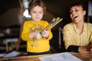 Genç Anne ve oğlu art Studio renk boya ile oynuyor. Fırçalar ve gülmek renk onlara kirli ellerle tutun