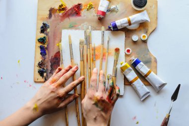 Eller farklı boya ve fırça sanat Studio ile dağınık kirli palette kadın sanatçının en üst noktasından vurdu. Beyaz arka plan