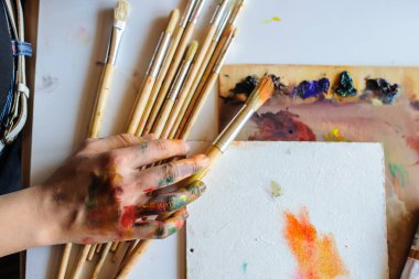 Eller farklı boya ve fırça sanat Studio ile dağınık kirli palette kadın sanatçının en üst noktasından vurdu. Beyaz arka plan