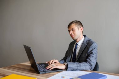 Bir iş adamı, proje bilgisayar, gri arka plan üzerinde arıyorsunuz bir ofis masası