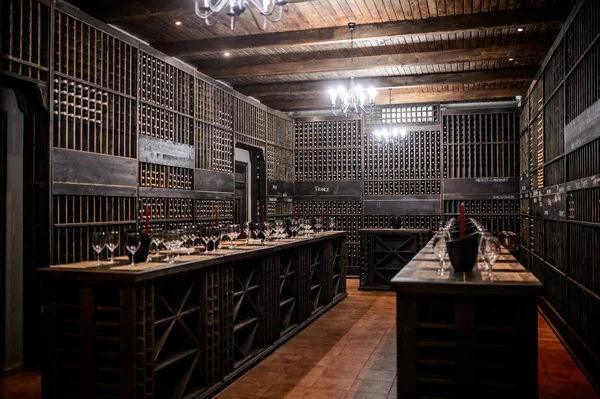 The wine room with a lot of buttles, wooden shelves and red candles