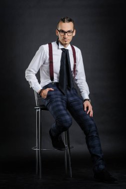 Beyaz gömlek kravat siyah arka plan ile sandalye üzerinde oturan genç yakışıklı çocuk