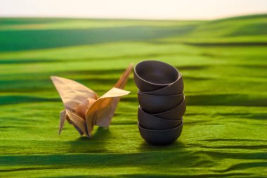 Üç bardak seramik ve bir origame görünümü Kapat, yeşil arka plan vinç