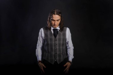 Yakışıklı beyaz genç adam beyaz bir gömlek ve ayakta, uzun saç, siyah arka plan seyir uygun