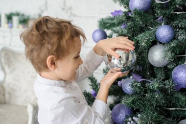 6 yıllık sarışın çocuk mor oyuncaklar ile Noel ağacı süsleme