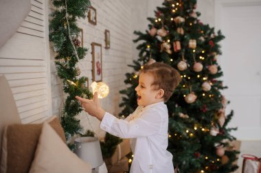 Noel ortamında elinde Noel ışıkları olan 6 yaşında sarışın bir çocuk.