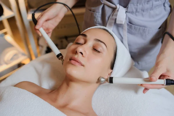 Kadının yüz masajı spa prosedürünün yan görüntüsü. Elektrikli yüz bakımı. Mikroakım kaldırma suratı. Güzellik spa prosedürü. Sağlık odasında yaşlanma karşıtı gençleştirme cerrahi olmayan tedavi