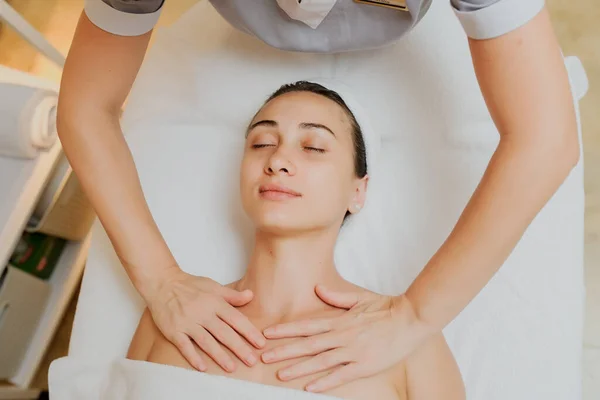 Close up head shot of Woman having curative upper chest massage. Therapist applying pressure with thumbs on upper chest.
