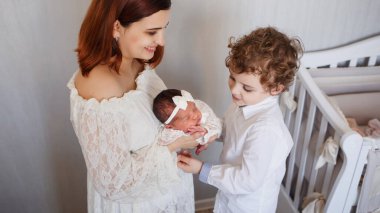 Anne ve kardeş yeni doğmuş tatlı bir kıza bakıyor.