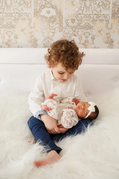 Big Brother His Newborn Sister His Arms Bed Covered White — Stock Photo, Image