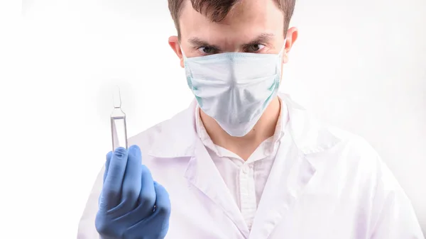Lekarz Masce Białym Mundurze Patrzący Ampułkę Lekiem Który Trzyma Ręku — Zdjęcie stockowe