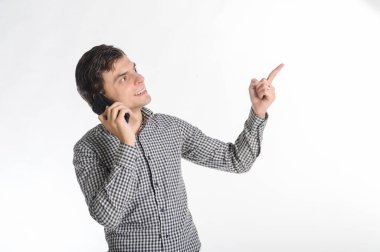 Gri elbiseli, 30 yıllık esmer bir adam beyaz bir arka planda cep telefonuyla konuşuyor.