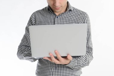 Gri elbiseli, 30 yıllık esmer bir adam laptopta beyaz bir arka planda çalışıyor.