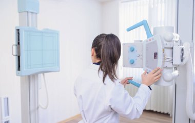 Geriye bakış: muayene sırasında röntgen cihazını ayarlayan bir kadın radyologun resmi