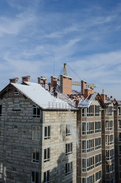 picture of workers cleaning the roof of a high building from snow with shovels